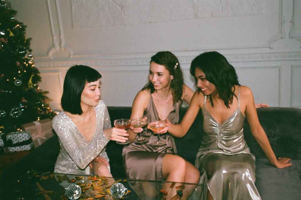 the holiday edit, women sitting on sofa at holiday party